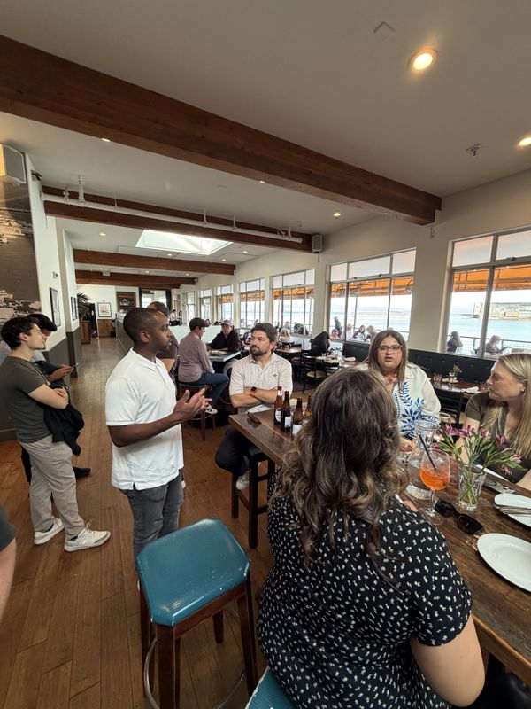 A group talking around a long restaurant table, with big windows looking out over the bay.